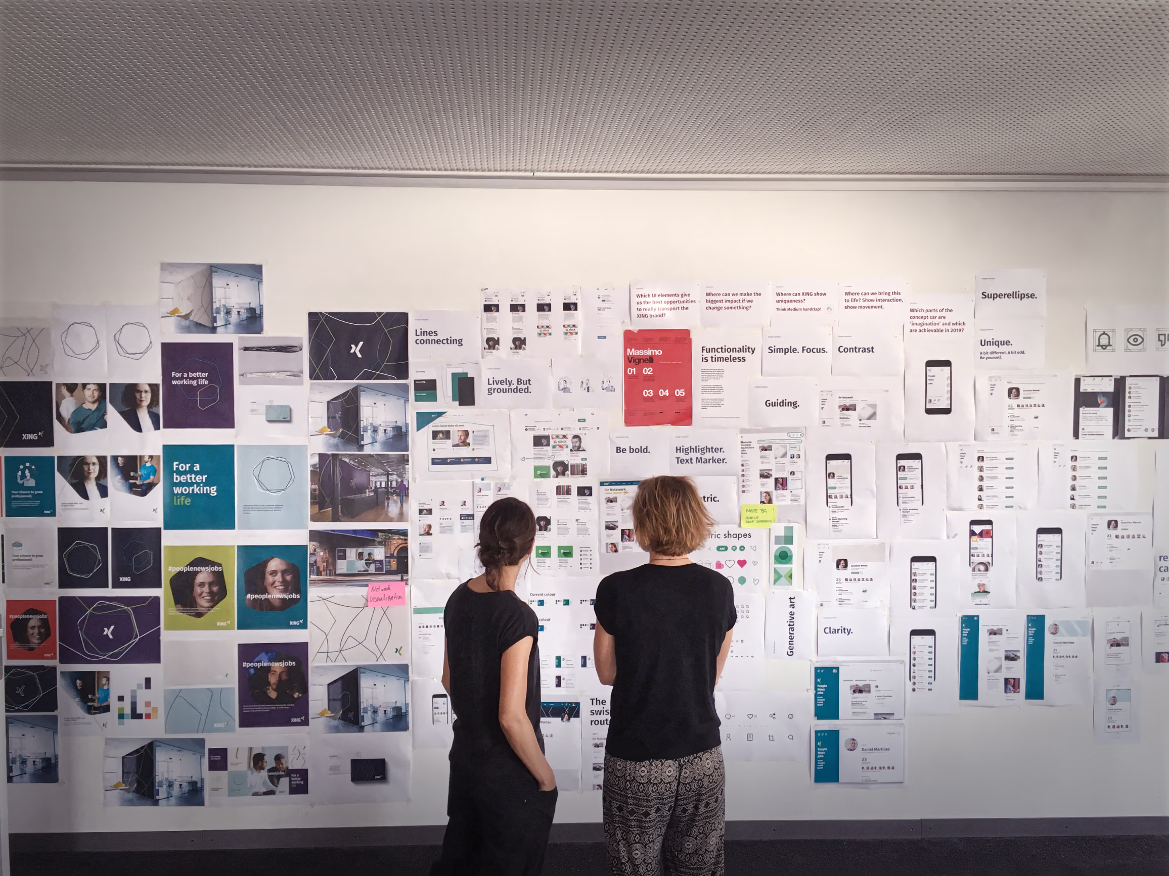 Team members standing in front of research boards and product screenshots during a design language workshop.