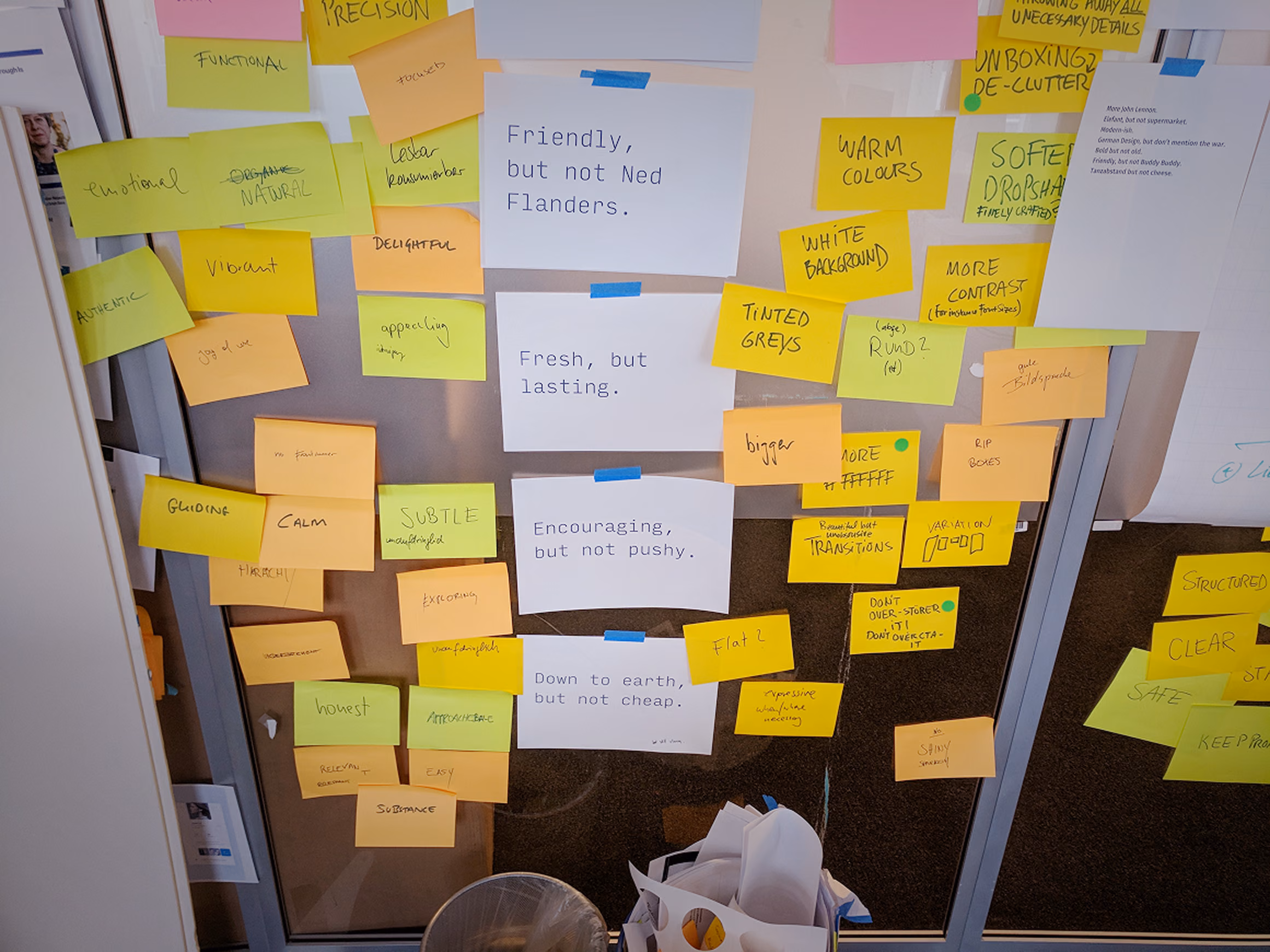 Workshop wall covered with yellow and pink sticky notes from an early design language sprint.