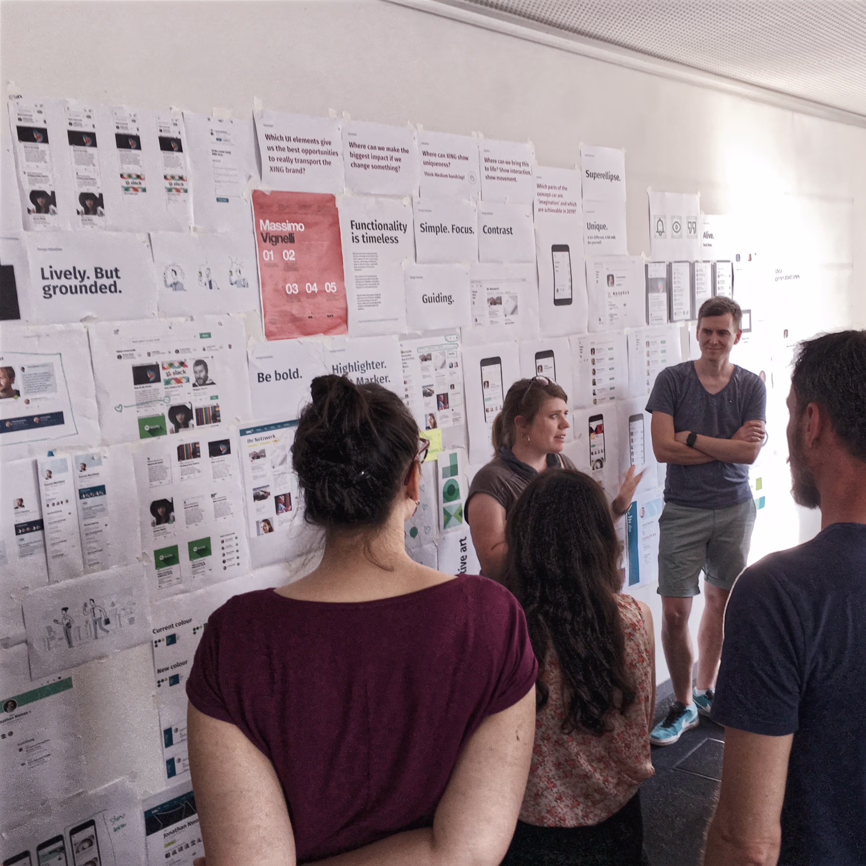 People reviewing sketches, screenshots and sticky notes on a wall during the product redesign process.